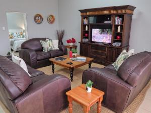 a living room with two couches and a tv at Poinsettia family Cottage in Hazyview