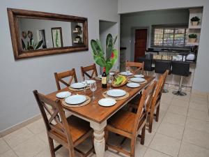 a wooden dining room table with chairs and a mirror at Poinsettia family Cottage in Hazyview