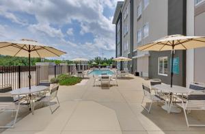 een patio met tafels en parasols en een zwembad bij La Quinta by Wyndham Starkville at MSU in Starkville