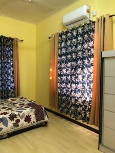 Villa Ungu Homestay في كوبانج كيريان: غرفة نوم بسرير وستائر في غرفة