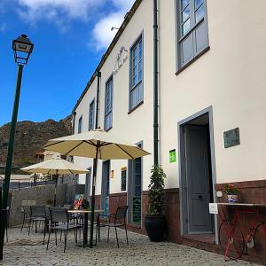 an outdoor patio with tables and umbrellas in front of a building at Hotel Rural Triana in Vallehermoso