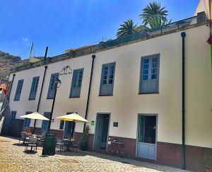 a building with tables and umbrellas in front of it at Hotel Rural Triana in Vallehermoso