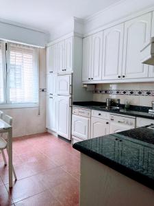 a kitchen with white cabinets and a black counter top at ZARAUTZ CENTRO Garaje-Parking-Free in Zarautz +7 photos