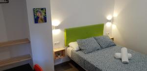 une petite chambre avec un lit et une tête de lit verte dans l'établissement Pensión La Estrella, à Saragosse