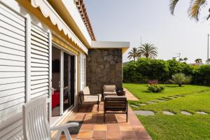 a patio with chairs and tables on a house at Bungalows Cordial Macaro Beach in Playa del Ingles