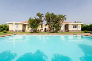 a large swimming pool in front of a house at Bungalows Cordial Macaro Beach in Playa del Ingles