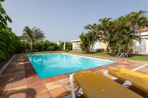 a swimming pool with two chairs and a house at Bungalows Cordial Macaro Beach in Playa del Ingles