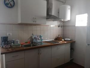 cocina con armarios blancos, fregadero y reloj en Casa La Terraza, en Vallehermoso