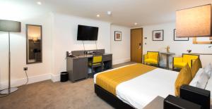 a hotel room with a bed, tv and a desk at The Park City Grand Plaza Kensington Hotel in London