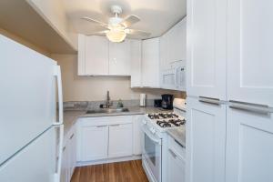 a white kitchen with white cabinets and a ceiling fan at Ocean View from Lanais-2 Blocks to Waikiki Beach in Honolulu