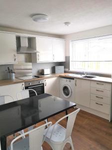 a kitchen with white cabinets and a table and chairs at No.20 in Borth