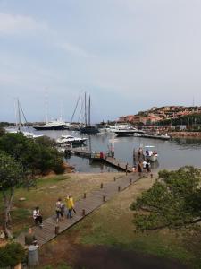 un gruppo di persone che camminano su un molo vicino a un porto turistico di Residenza Chrysalis Bay a Porto Cervo