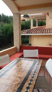 a patio with a red couch and white chairs at villa PICOZZI cannigione in Cannigione