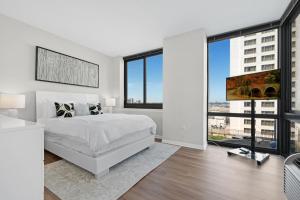 - une chambre avec un lit blanc et de grandes fenêtres dans l'établissement Global Luxury Suites Downtown Jersey City, à Jersey City