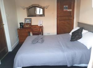 a bedroom with a bed with a dresser and a mirror at The Olde Swan Hotel in Chertsey