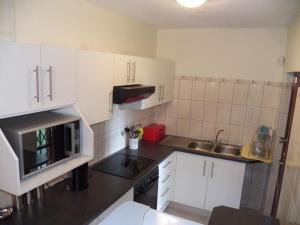 una pequeña cocina con armarios blancos y microondas en 26 Pelser Plaat Meerensee en Richards Bay