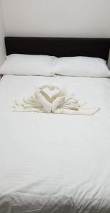 a white bed with a heart shaped towel on it at JSK Apartment in Bacoor
