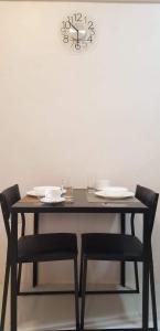 stół z krzesłami i zegar na ścianie w obiekcie JSK Apartment w mieście Bacoor