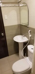 a bathroom with a sink and a toilet and a mirror at JSK Apartment in Bacoor