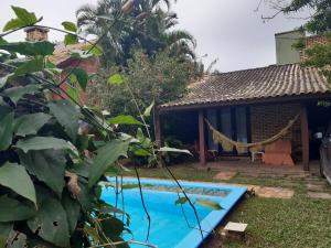a house with a swimming pool in the yard at Casa Rústica praia da Ferrugem próximo praia com piscina compartilhada in Garopaba