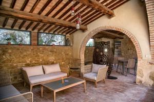 une terrasse avec des chaises, une table et une arche dans l'établissement Palazzo Massaini - Cavarciano, à Pienza