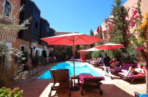 een zwembad met tafels en parasols en mensen die er omheen zitten bij Les Borjs De La Kasbah in Marrakesh