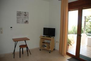sala de estar con TV, mesa y escritorio en Villa with a pool in Lefkogia en Lefkogeia