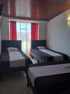 パイパにあるHotel Hortensia Realのベッド2台、赤いカーテン付きの窓が備わる客室です。