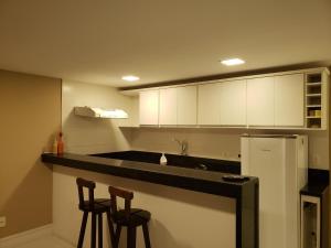 eine Küche mit zwei Stühlen und einer Theke mit Kühlschrank in der Unterkunft Búzios Loft charmoso in Búzios