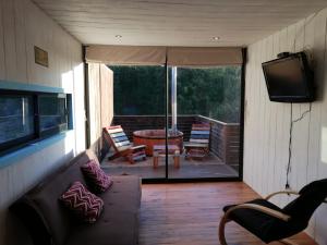 a screened in porch with a couch and a television at Cabañas Paidahue Pichilemu in Pichilemu