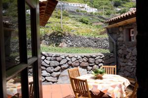 a table and chairs on a patio with a stone wall at Casas Dos Vimes in Fajã dos Vimes