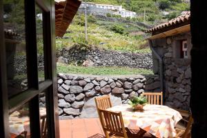 a table and chairs on a patio with a stone wall at Casas Dos Vimes in Fajã dos Vimes +75 photos