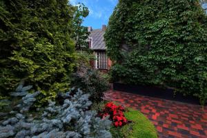 a garden with red flowers in front of a house at Second Floor Apartament in Liepāja +6 photos
