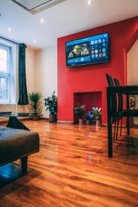a living room with a red wall with a flat screen tv at Hotel Quality Stay,2 bed Apartment near the City Centre, 2min Walk from Metro Station in London