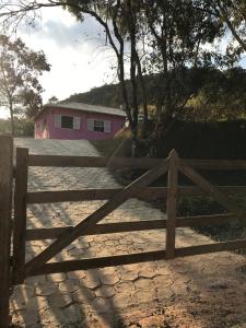 einen Holzzaun vor einem rosa Haus in der Unterkunft Casa Ibitipoca in Conceição da Ibitipoca