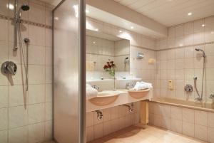 a bathroom with two sinks and a tub and a mirror at Gasthof Valluga in Sankt Christoph am Arlberg