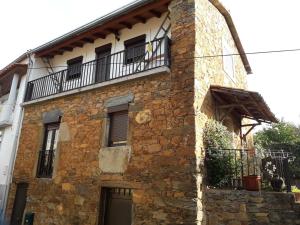 ein altes Steingebäude mit Balkon oben in der Unterkunft A casinha da Aldeia de Xisto in Fundão