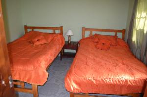 two beds with orange covers in a room at Hotel la Cabaña in El Cocuy