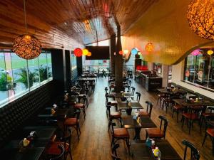 an empty restaurant with tables and chairs and windows at Herval Park Hotel in Ponta Porã