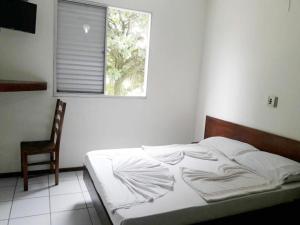 ein Bett in einem Schlafzimmer mit einem Fenster und einem Stuhl in der Unterkunft USCEESP Itanhaem in Itanhaém