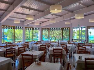 un ristorante con tavoli e sedie bianchi e finestre di Hotel Paradiso a Portoferraio
