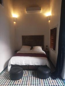 1 dormitorio con 1 cama con 2 taburetes en Dar Faracha Fes, en Fez