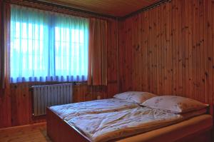 a bed in a wooden room with a window at Dom u Małgosi in Witów