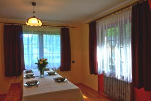 una mesa con un jarrón de flores en una habitación con ventanas en Dom u Małgosi, en Witów