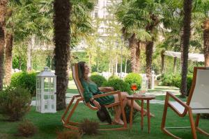 a woman sitting in a chair in a yard at Hotel Savoia Thermae & SPA in Abano Terme