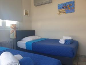 a room with two beds with blue sheets at Periyiali Beach Sunset Suite A7 in Perivolia