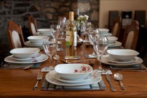 a table with plates and glasses and a bottle of wine at Merlin Cottages in Llandovery +19 photos