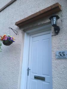 a building with a white door with a sign and a flower pot at situated at the heart of fort william in Fort William