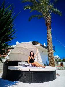 PIOTROWSKI APARTMENTS في ثيولوغوس: امرأة تجلس على سرير على الشاطئ
