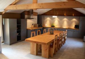 une grande cuisine avec une table et des chaises en bois dans l'établissement Le Rouet, à La Gleize